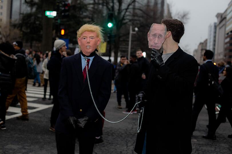 Zwei Männer machen sich bei einer Demonstration in Washington über das Verhältnis zwischen ihm und dem Russischen Präsidenten Putin lustig.