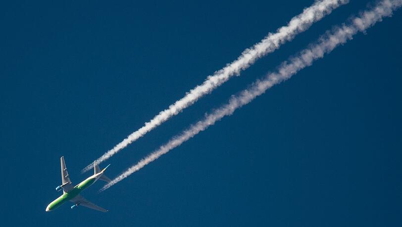 Ein Flugzeug hinterlässt Kondensstreifen am Himmel. Spätestens Mitte des Jahrhunderts soll schließlich mit grünem Wasserstoff geflogen werden.