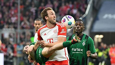 Münchens Harry Kane (M) kämpft gegen Mönchengladbachs Rocco Reitz (l) und Manu Kone um den Ball.
