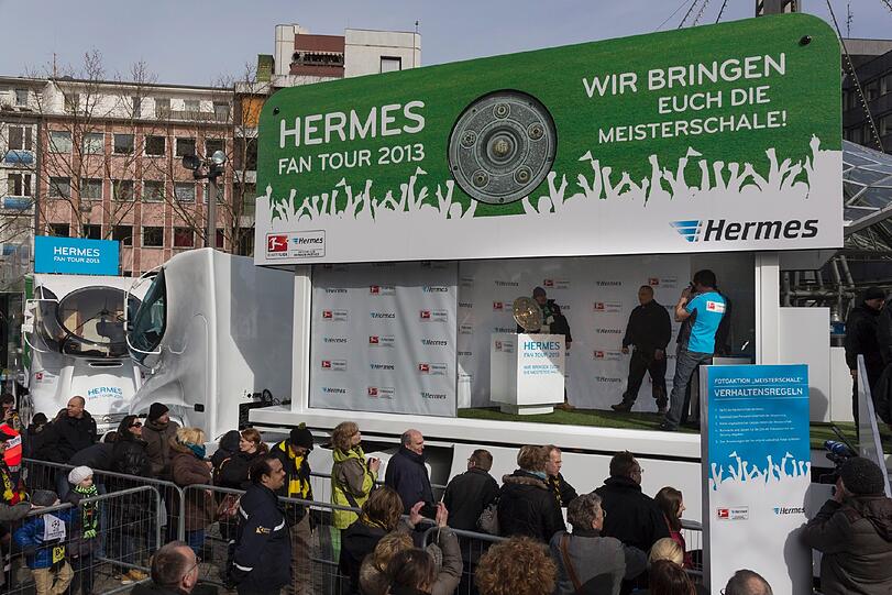 Hermes zeigt die Meisterschale ganz nah.