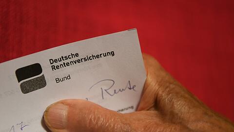 Eine ältere Frau hält ihren Rentenbescheid in der Hand.