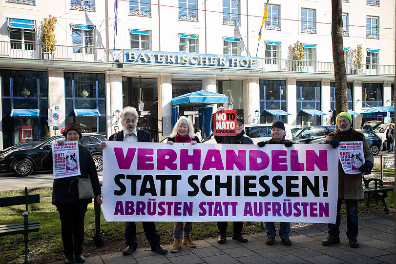 Aktivist*innen vom Bündnis gegen die NATO-Sicherheitskonferenz demonstrierten am 15.2.2023 in München mit einer kleinen Fotoaktion vor dem Tagungsort Bayerischer Hof der Münchner Sicherheitskonferenz.