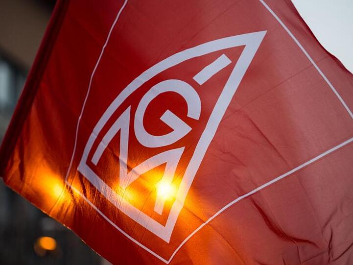 Eine Fahne mit dem Logo der IG-Metall wird geschwenkt. Foto: Lino Mirgeler/Archiv