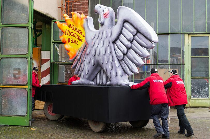 Mitglieder der Zugbegleitung schieben in Düsseldorf einen Motivwagen in die Bauhalle.