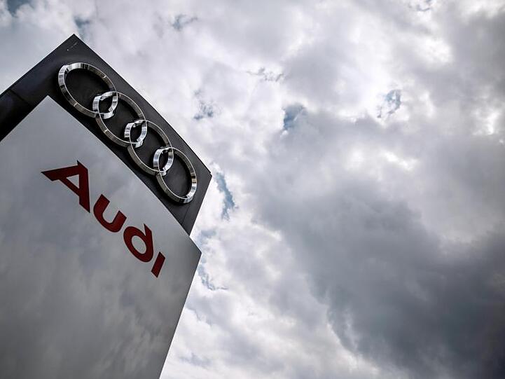 Dunkle Wolken ziehen über eine Stele mit dem Audi-Logo. Foto: Christoph Schmidt/Archivbild