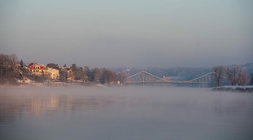 Wasserdampf schwebt bei eisigen Temperaturen über der Elbe in Dresden. Im Hintergrund die Brücke "Blaues Wunder".