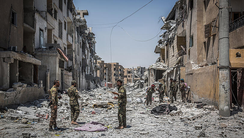 Soldaten der Syrischen Demokratischen Kräfte gehen in Al-Rakka durch einen zerstörten Straßenzug. Soldaten der Syrischen Demokratischen Kräfte gehen in Al-Rakka durch einen zerstörten Straßenzug.