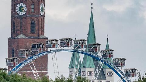 Ein Riesenrad steht auf dem Gelände des Gäubodenvolksfestes vor dem Stadtturm und der Basilika St. Jakob. Foto: Armin Weigel/Archivbild
