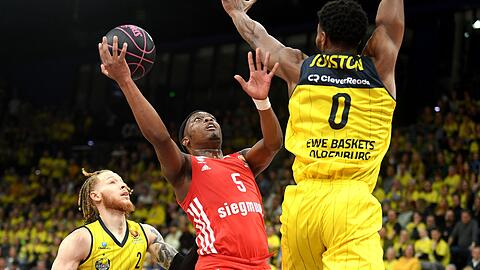 Cassius Winston (M.) vom FC Bayern kommt gegen Oldenburgs Hassani Gravett (l.) und Shakur Juiston zum Wurf.