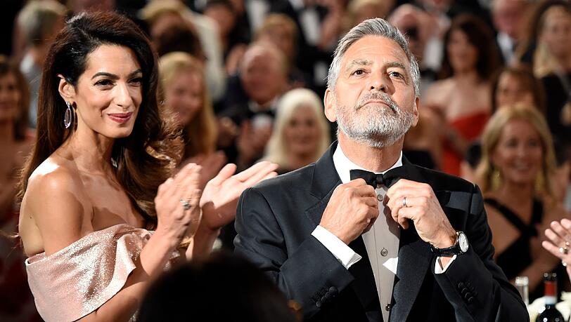 Glamourpaar im Spotlight: Schauspieler und Regisseur George Clooney richtet seine Fliege, seine Frau Amal applaudiert. Der zweifache Oscar-Preisträger („Syriana“, „Argo“) bekommt im Juni in Los Angeles (USA) den AFI-Preis für sein Lebenswerk – und wird für sein humanitäres Engagement geehrt. Glamourpaar im Spotlight: Schauspieler und Regisseur George Clooney richtet seine Fliege, seine Frau Amal applaudiert. Der zweifache Oscar-Preisträger („Syriana“, „Argo“) bekommt im Juni in Los Angeles (USA) den AFI-Preis für sein Lebenswerk – und wird für sein humanitäres Engagement geehrt.
