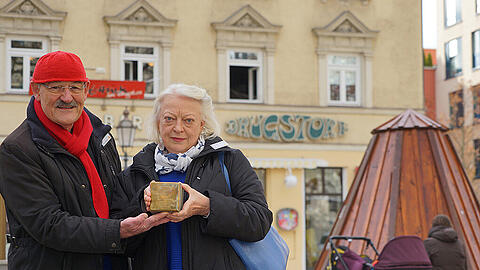 Klaus und Janne Weinzierl am Wedekindplatz. Sie halten einen Stolperstein in den Händen.
