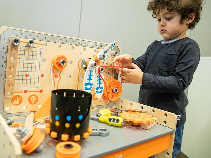 Kaan spielt am Rande der Pressekonferenz zur Spielwarenmesse 2019 mit der Werkbank Deluxe Scientific Workbench. Kaum ein Produkt dort kommt ohne technische Spielerei aus.