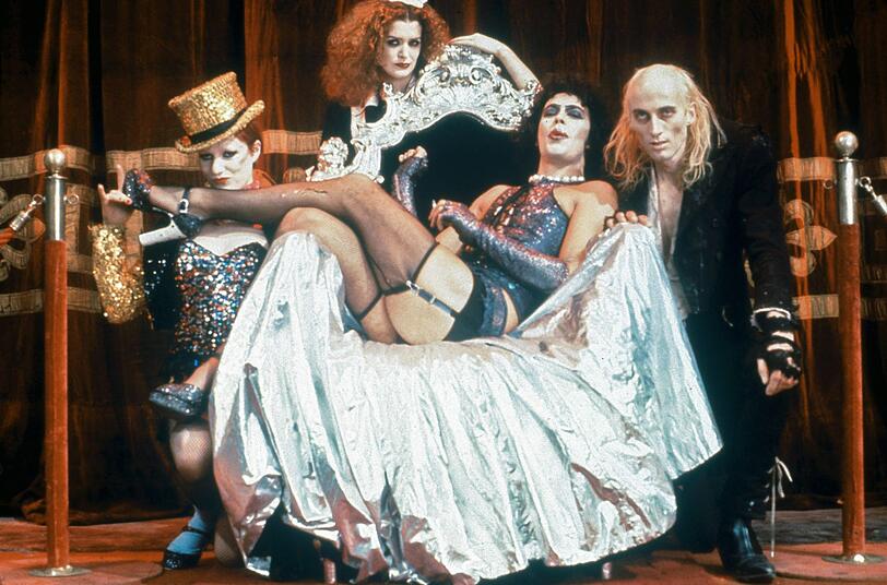 Der exzentrische Doktor Frank-N-Furter (Tim Curry, Zweiter von rechts) l&auml;sst sich von seinen Angestellten Columbia (Nell Campbell, links), Magenta (Patricia Quinn, Zweite von links) und Riff Raff (Richard O'Brien) bewundern.