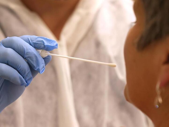 Ein Arzt nimmt in einer Hausarztpraxis mit einem Tupfer einen Abstrich für einen Coronatest.