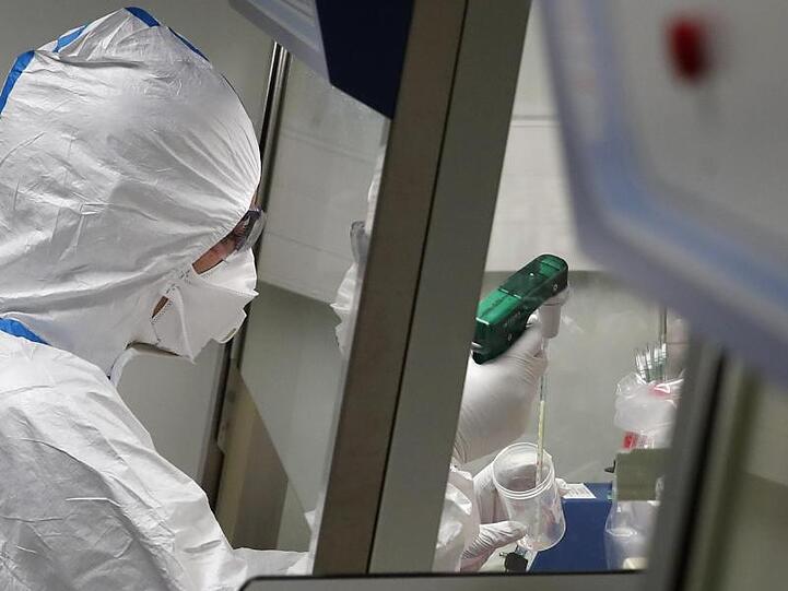 Ein Laborwissenschaftler in Schutzkleidung arbeitet mit Proben von Patienten, die mit dem Coronavirus infiziert sind. Foto: Francois Mori/AP/dpa/Archiv