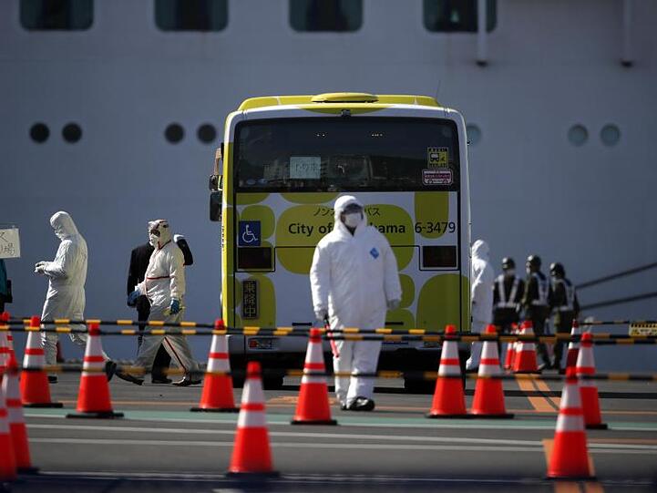 Ein Bus wird inspiziert, bevor die ersten Passagiere des unter Quarantäne stehenden Kreuzfahrtschiffs "Diamond Princess" einsteigen.