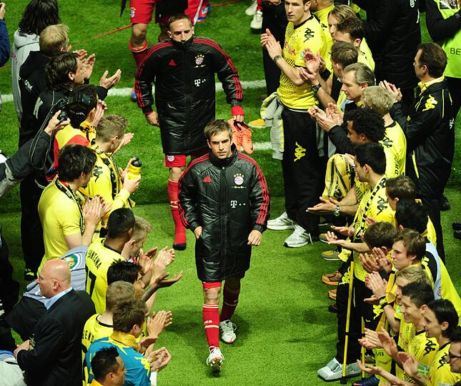 Phlipp Lahm geht vorbei an den siegreichen BVB-Spielern, die Spalier stehen und klatschen.