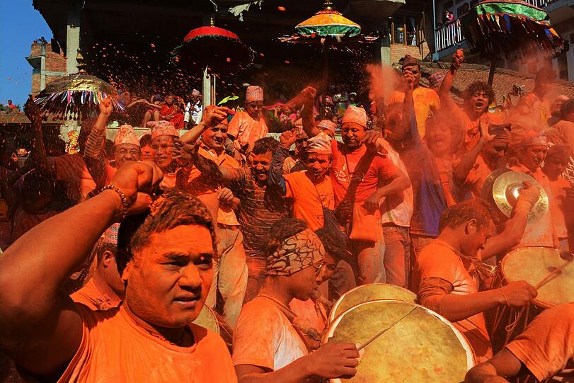 Nepalesische Nachtschwärmer werfen zinnoberrotes Puder durch die Luft während des Bisket Jatra Festivals zur Nepalesischen Neujahrsfeier.