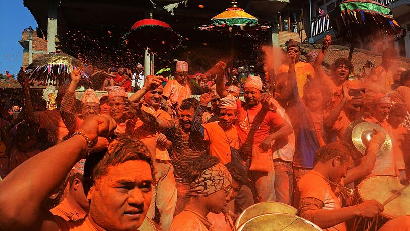 Nepalesische Nachtschwärmer werfen zinnoberrotes Puder durch die Luft während des Bisket Jatra Festivals zur Nepalesischen Neujahrsfeier. Nepalesische Nachtschwärmer werfen zinnoberrotes Puder durch die Luft während des Bisket Jatra Festivals zur Nepalesischen Neujahrsfeier.
