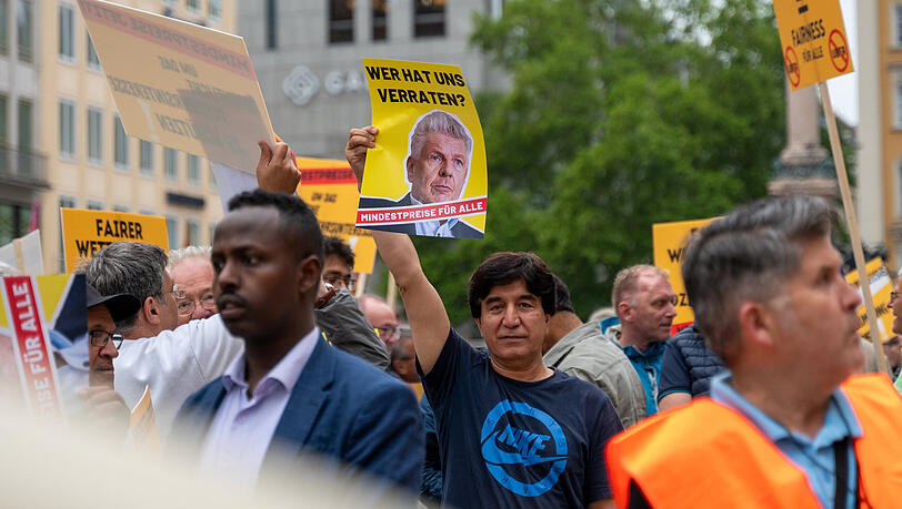Ein Mann hält bei einer Demonstration von Taxifahrern auf dem Münchner Marienplatz ein Schild mit der Aufschrift "Wer hat uns verraten? – Mindestpreise für alle" in die Höhe. Auf dem Schild ist ein Bild von Münchens OB Dieter Reiter zu sehen. Ein Mann hält bei einer Demonstration von Taxifahrern auf dem Münchner Marienplatz ein Schild mit der Aufschrift "Wer hat uns verraten? – Mindestpreise für alle" in die Höhe. Auf dem Schild ist ein Bild von Münchens OB Dieter Reiter zu sehen.