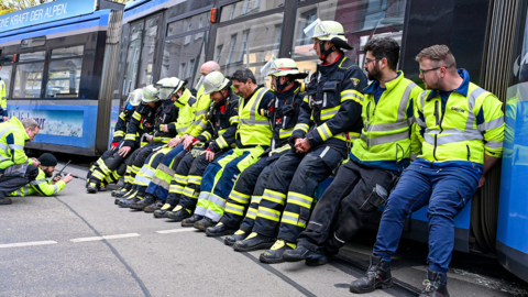 Einsatzkräfte der Feuerwehr helfen, die Tram wieder in die Gleise zu bewegen.