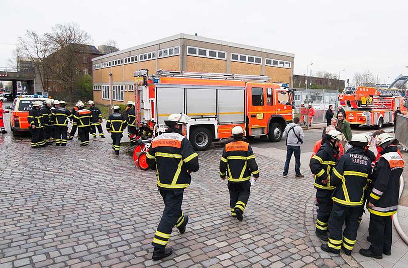 Feuerwehrleute stehen in Hamburg-Hammerbrook vor einer Flüchtlingsunterkunft. In einem Wohncontainer auf dem Gelände ist ein Brand ausgebrochen.