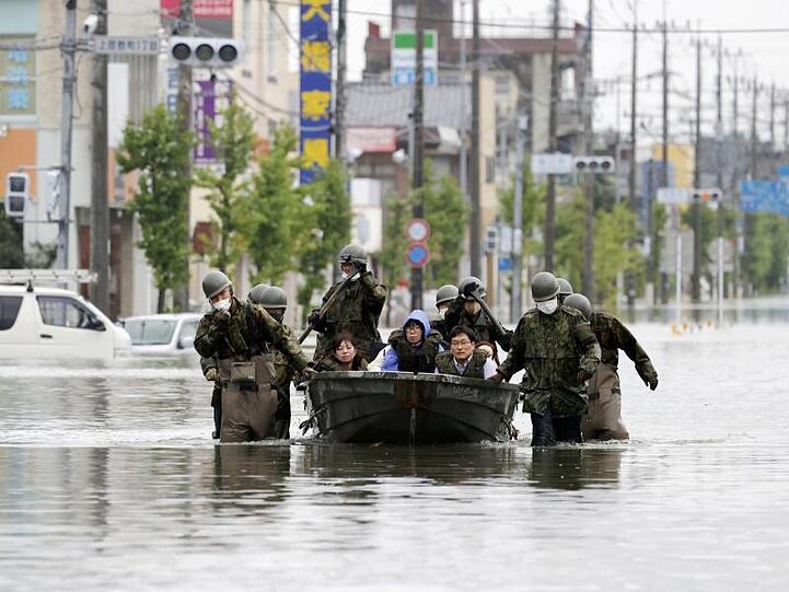 Japanische Soldaten beim Rettungseinsatz in den überschwemmten Straßen von Omuta.