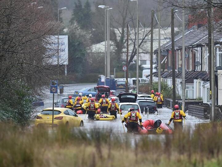 Im walisischen Nantgarw sind Rettungskräfte auf einer überschwemmten Straße im Einsatz.