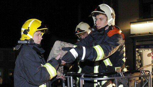Feuerwehrmänner mit Teilen eines Schornsteins Feuerwehrmänner mit Teilen eines Schornsteins