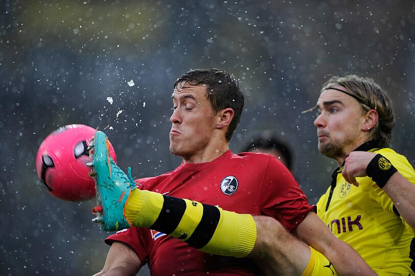 Die Bilder aus Freiburg. Die Linien müssen freigeräumt werden, der Ball ist rot und Spieler wie Trainer sind nicht zu beneiden. Doch dennoch wird gespielt.