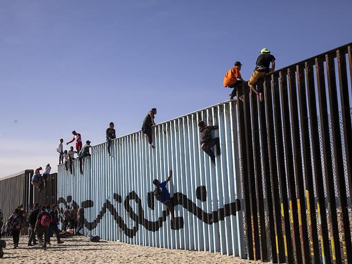 Flüchtlinge sitzen bei Tijuana auf dem Grenzzaun zwischen Mexiko und den USA. Nach einer Tausende Kilometer langen Reise haben die ersten Migranten aus Mittelamerika die Grenze erreicht.