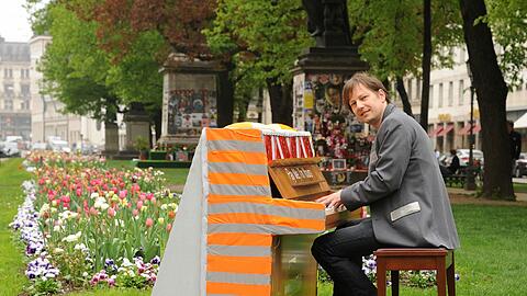 Künstler Stefan 
Künstler Stefan Wischnewski sitzt am Wanderklavier am Promenadeplatz. Er hat es selbst gestaltet und spielt sich schon mal warm.