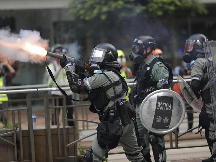 Ein Polizist setzt Tränengas gegen Demonstranten ein.