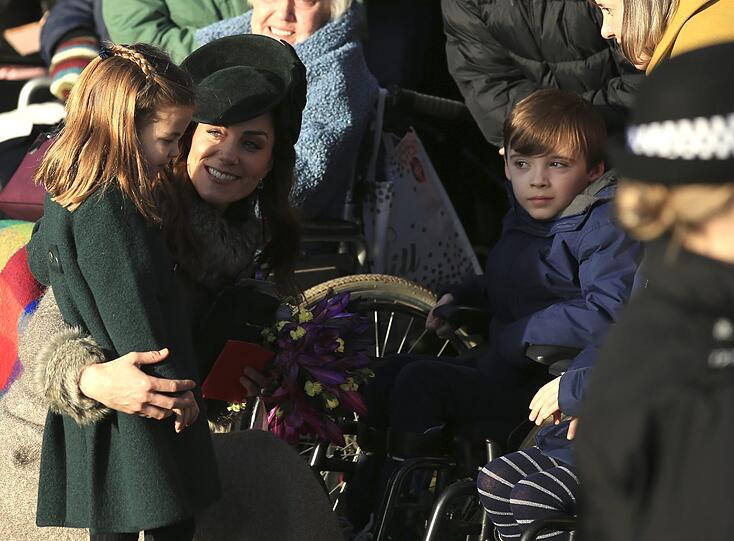 Herzogin Kate und ihre Tochter Prinzessin Charlotte begrüßen einen im Rollstuhl sitzenden Jungen