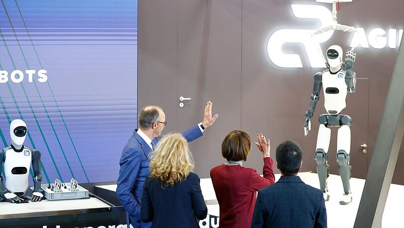 Bundeskanzler Friedrich Merz winkt einem Roboter zu &ndash; die Zukunft winkt zur&uuml;ck.