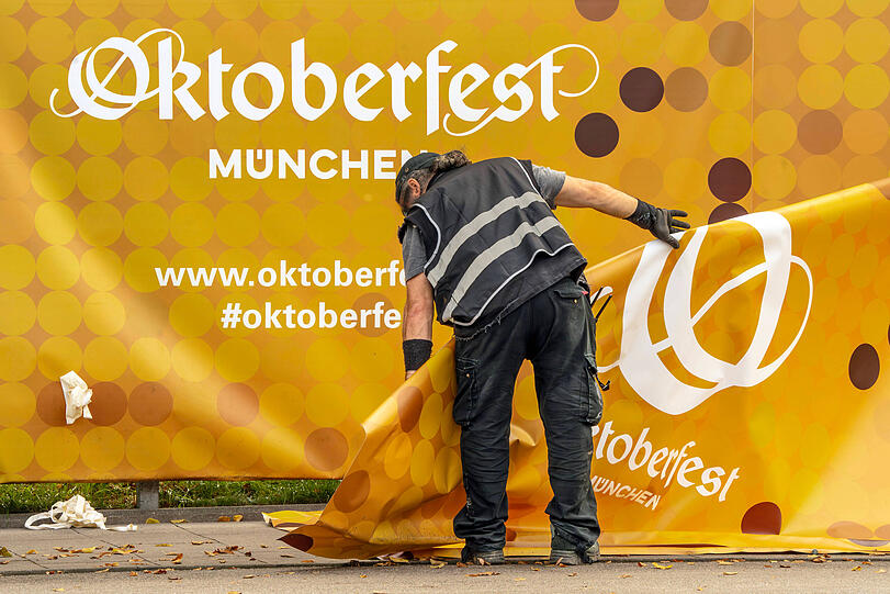 Die Planen mit dem Oktoberfest-Logo am Zaun werden entfernt.
