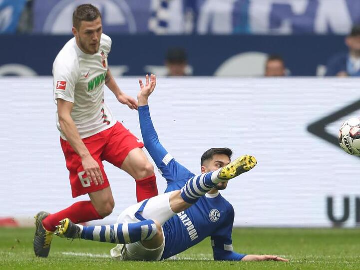 Schalkes Suat Serdar (r.) schießt den Ball vor Jeffrey Gouweleeuw (l.) aus Augsburg weg. Foto: Friso Gentsch