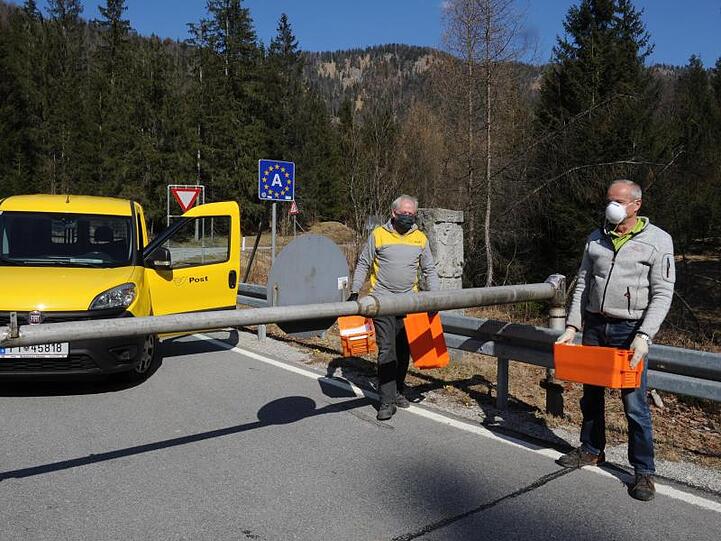 Zwei Postboten stehen an der Schranke an der Grenze von Deutschland zu Österreich. Foto: Ursula Düren/dpa