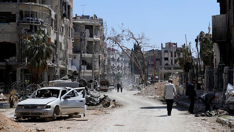 Menschen gehen an zerstörten Häusern und Autos im Vorort der syrischen Hauptstadt Damaskus vorbei. Der Westen macht die syrische Regierung für den mutmaßlichen Einsatz von Chemiewaffen in der ehemaligen Rebellenhochburg Duma verantwortlich. Menschen gehen an zerstörten Häusern und Autos im Vorort der syrischen Hauptstadt Damaskus vorbei. Der Westen macht die syrische Regierung für den mutmaßlichen Einsatz von Chemiewaffen in der ehemaligen Rebellenhochburg Duma verantwortlich.