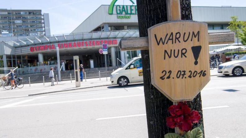 Ein Holzkreuz mit der Aufschrift "Warum nur! - 22.07.2016" hängt vor dem Eingang zum Olympia-Einkaufszentrum (OEZ). (Archivfoto)