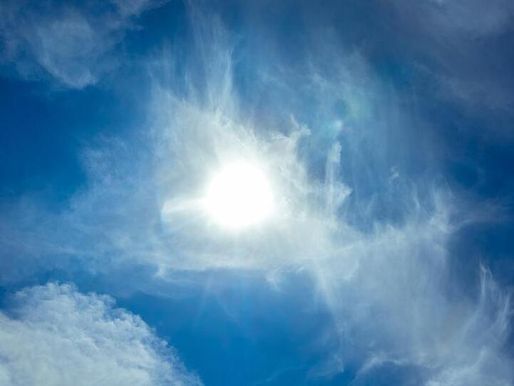 Die Sonne scheint am Himmel durch eine Wolke hindurch. Foto: Markus Scholz/dpa/Archivbild