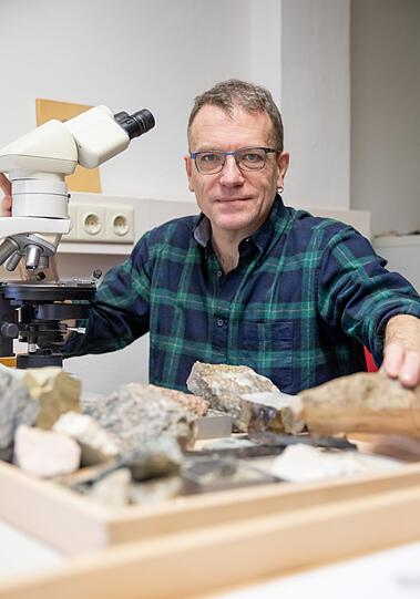 Daniel Köhn, Professor für Tektonik, sitzt in der Universität in Erlangen an einem Mikroskop.
