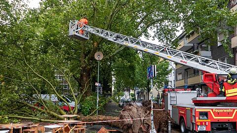 Nach einem kurzen und heftigen Gewitter liegt in Bochum ein umgestürzter Baum neben dem Außenbereich einer Eisdiele.