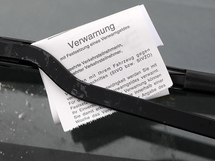 Ein "Knöllchen" für einen Falschparker ist unter dessen Scheibenwischer geklemmt.
