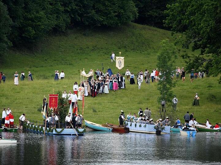 Gläubige gehen bei der Fronleichnams-Seeprozession am Staffelsee von der Insel Wörth wieder zu ihren Booten. Foto: Angelika Warmuth