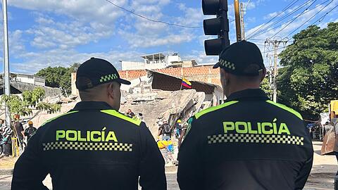 Polizisten stehen vor einem abgest&uuml;rzten Geb&auml;ude.