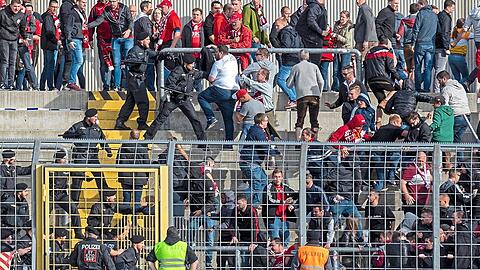 Polizisten mit gezücktem Schlagstock stürmen nach Schlusspfiff in den Gästeblock des Grünwalder Stadions.