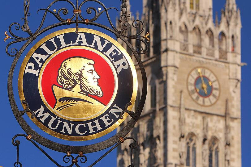 Logo der Brauerei Paulaner an einer Gaststätte mit Turm des Rathaus es in der Innenstadt München Logo der Brauerei Paulaner an einer Gaststätte mit Turm des Rathaus es in der Innenstadt München