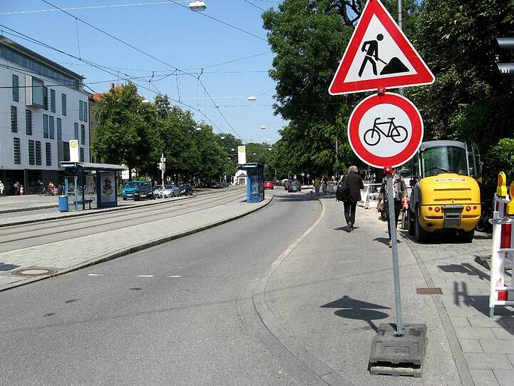 Weil Baumaschinen den gehweg blockieren, laufen die Fußgänger nun kreuz und quer über den Radlweg - der noch dazu mit Sand und Kies zur Schlitterbahn wird. Das entsprechende Warnschild steht mitten auf dem Radweg - auch das noch!