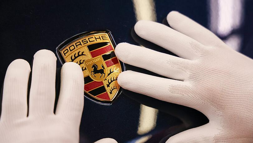 Ein Mitarbeiter befestigt in der "Exterieur Linie" eines Porsche Werks das Wappen an einem Porsche Macan.